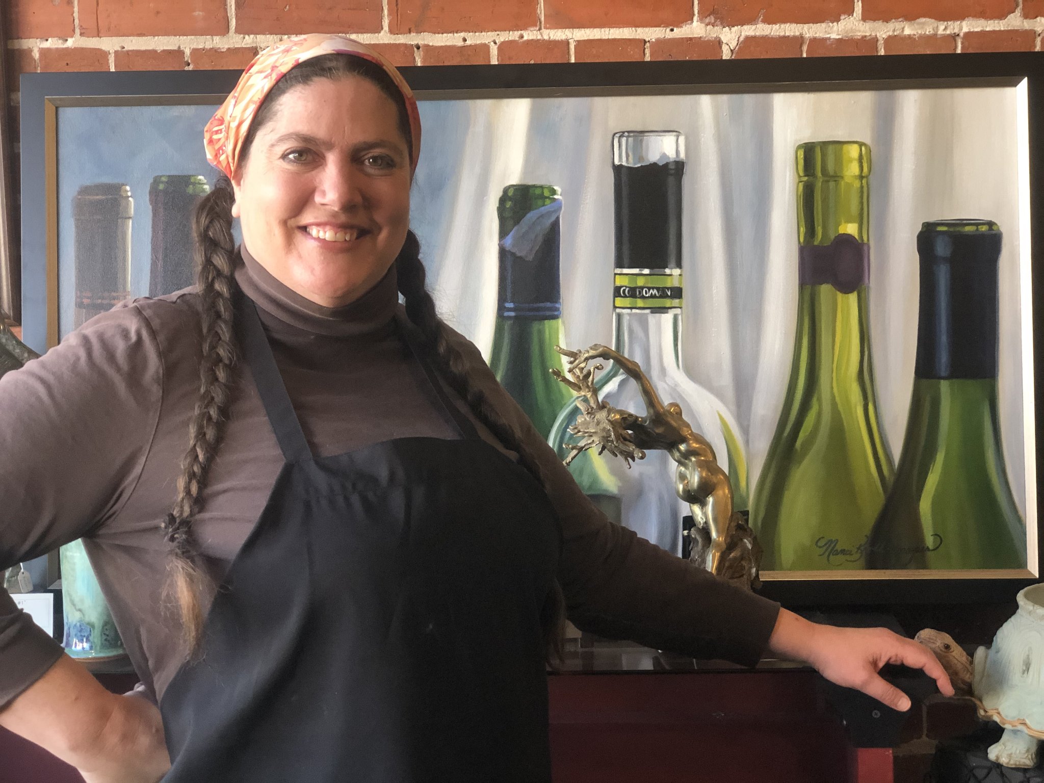 Root Cafe owner in front of wine bottle painting, Fennville Michigan