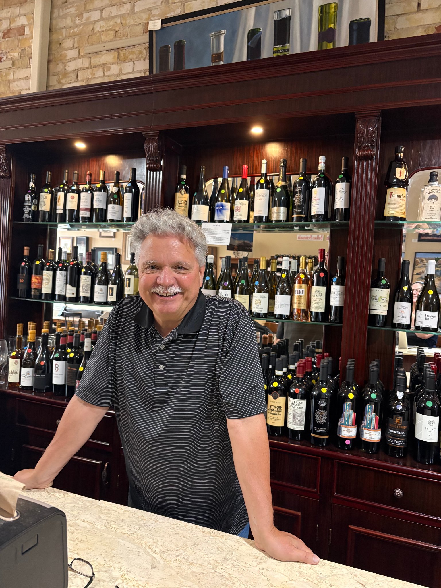 Root Cafe owner behind the bar with wine selection, Fennville Michigan